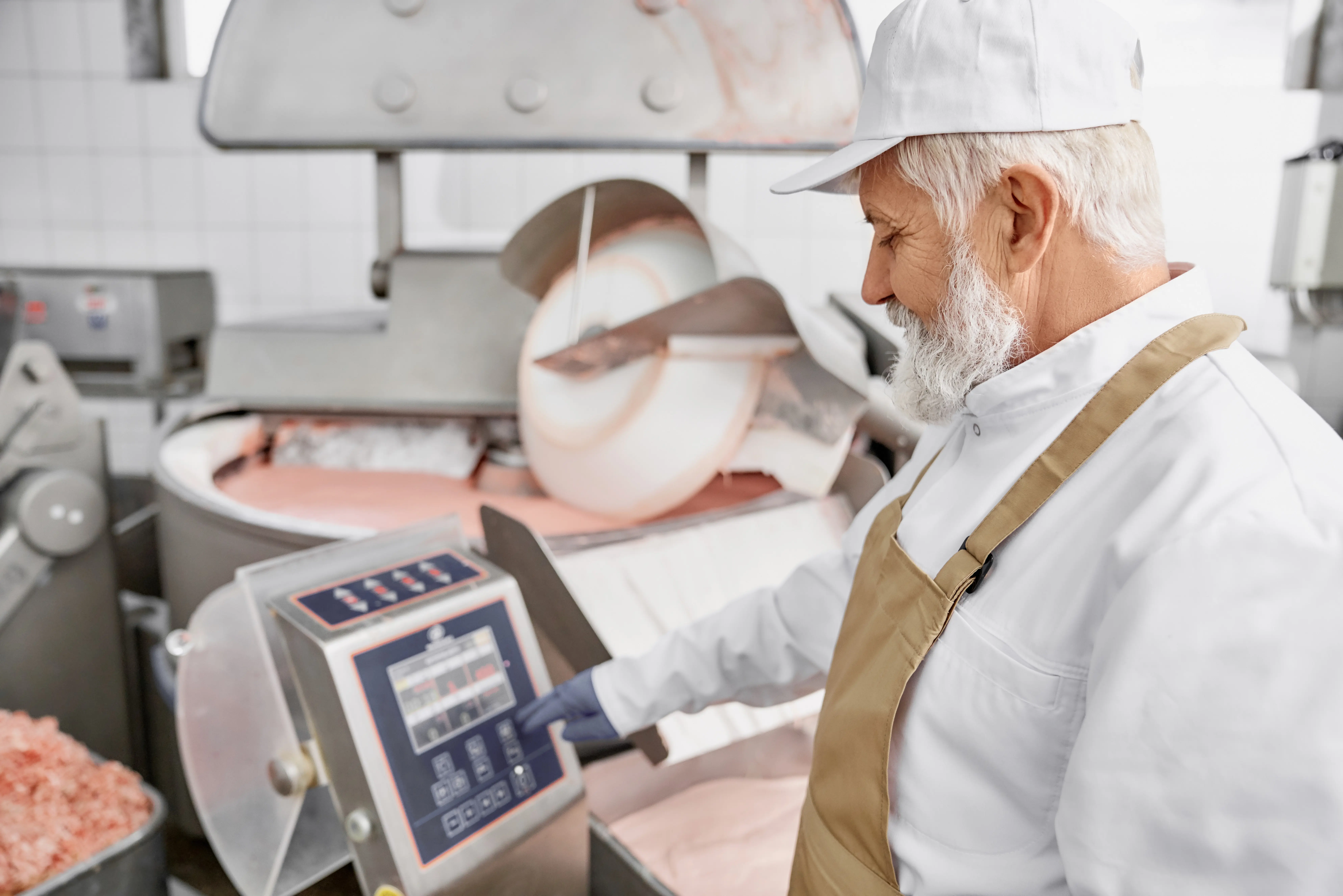 worker standing near equipment for grinding meat 2023
